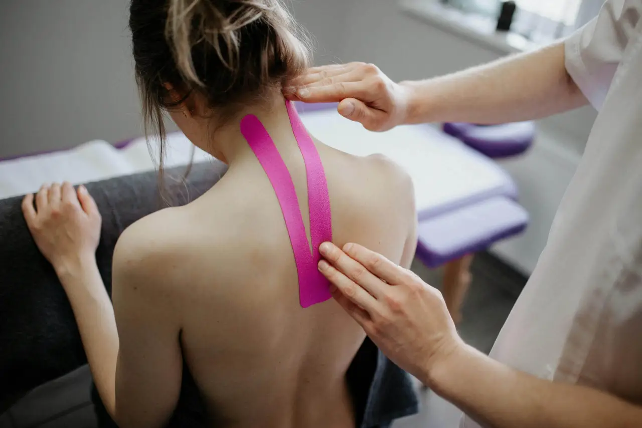 Physiotherapeutin behandelt eine Patientin mit manuellen Techniken zur Schmerzlinderung und Bewegungsverbesserung mit Tapes.